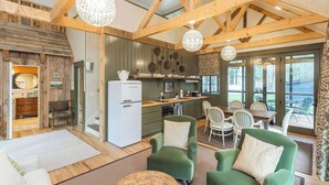Un interior rústico con vigas de madera a la vista, una cocina con electrodomésticos modernos y un comedor con vistas.