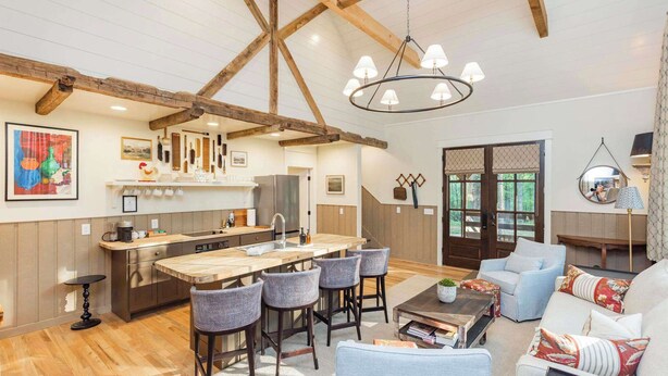 Amplia sala de estar con techo de madera, una isla central con taburetes, un sofá y una mesa de centro.