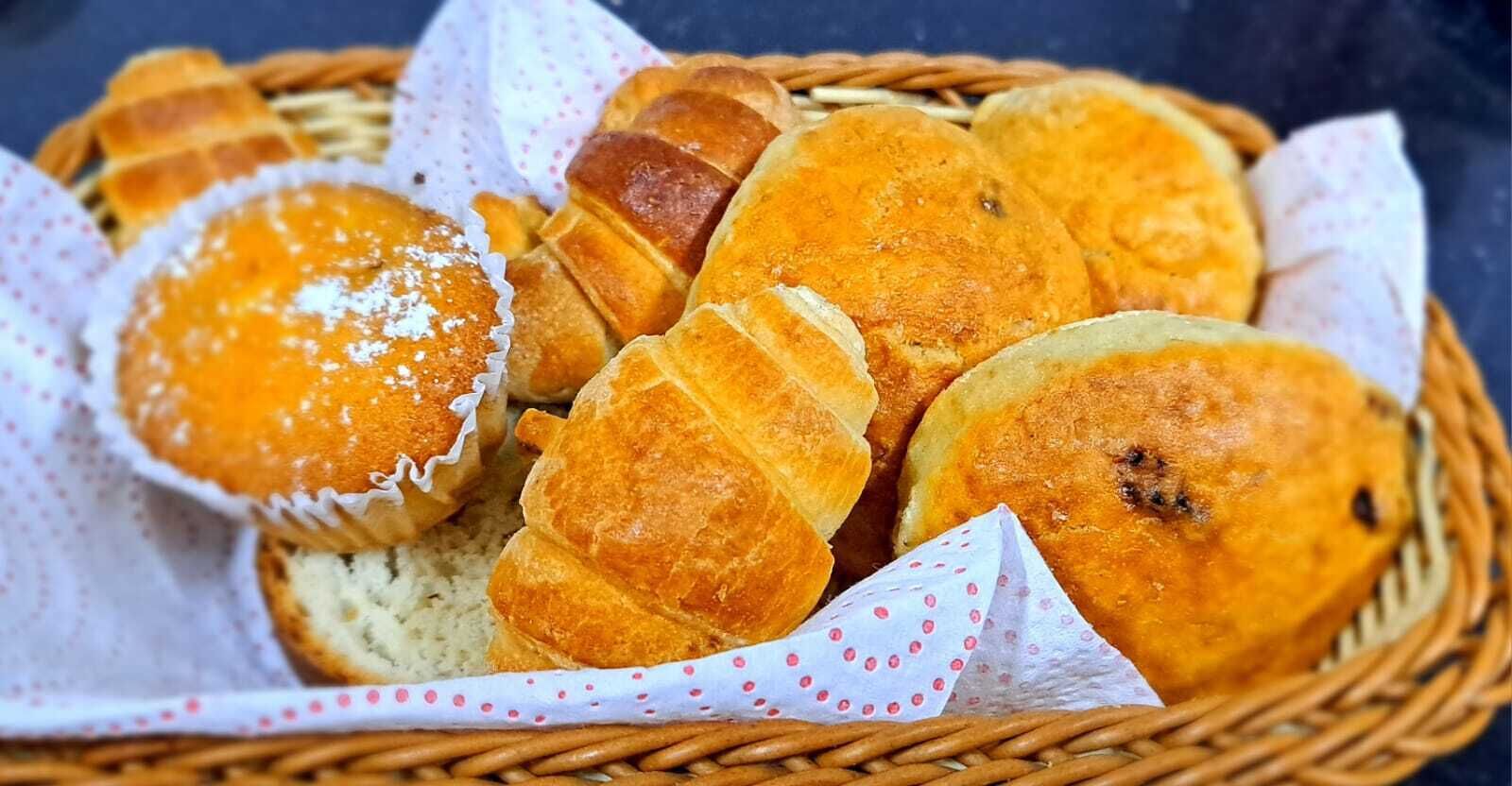 Una cesta con diversos productos horneados, como muffins y panes, dispuesta en una cesta de mimbre.