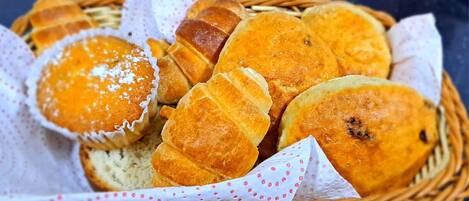 Una cesta con diversos productos horneados, como muffins y panes, dispuesta en una cesta de mimbre.
