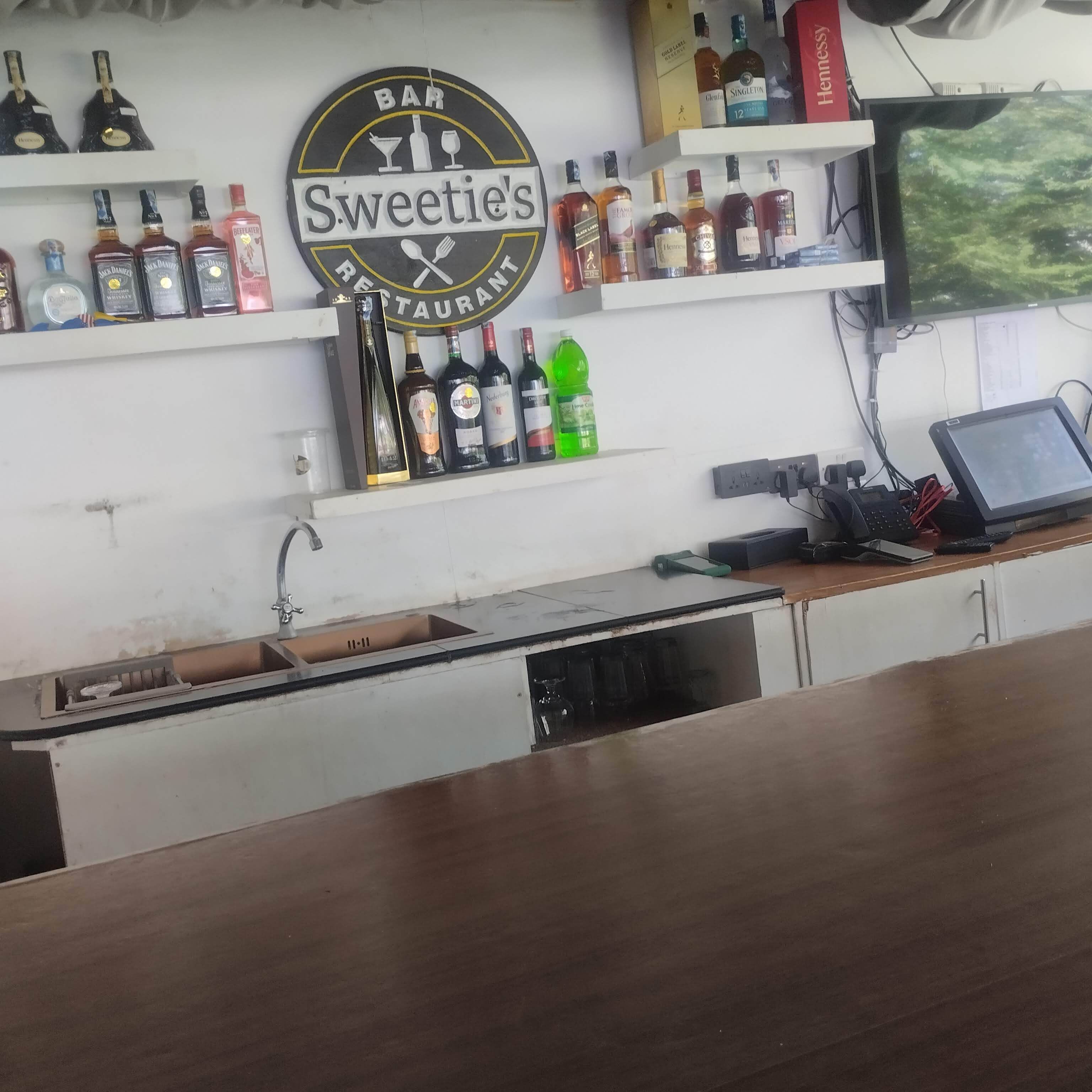 Een barruimte met drankflessen op de planken, een bordje met de tekst 