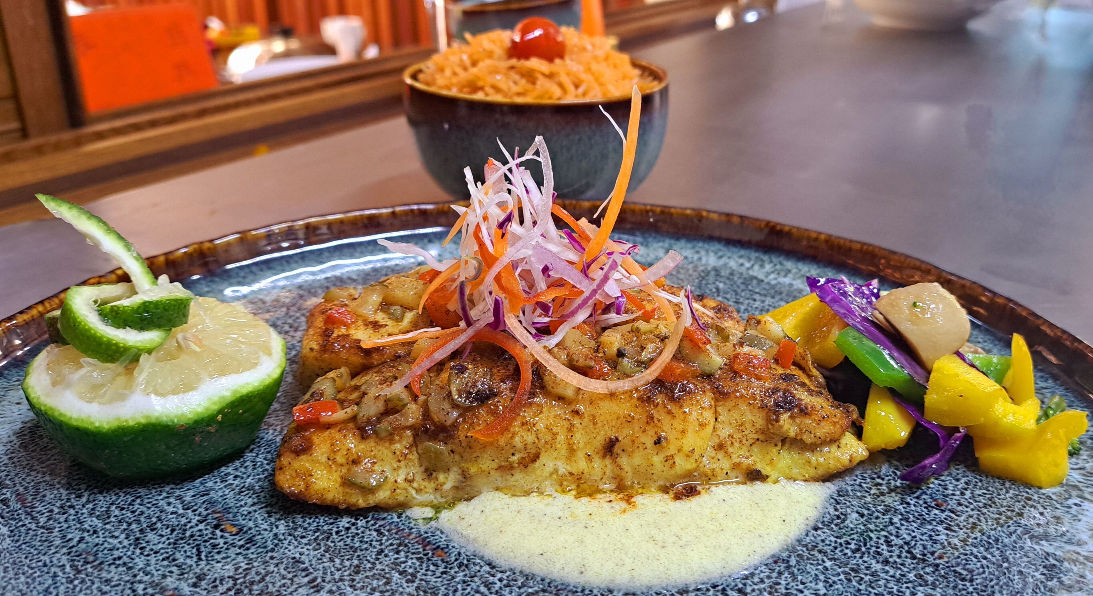 A plate of food with a lime wedge, a bowl of rice, and a variety of vegetables.