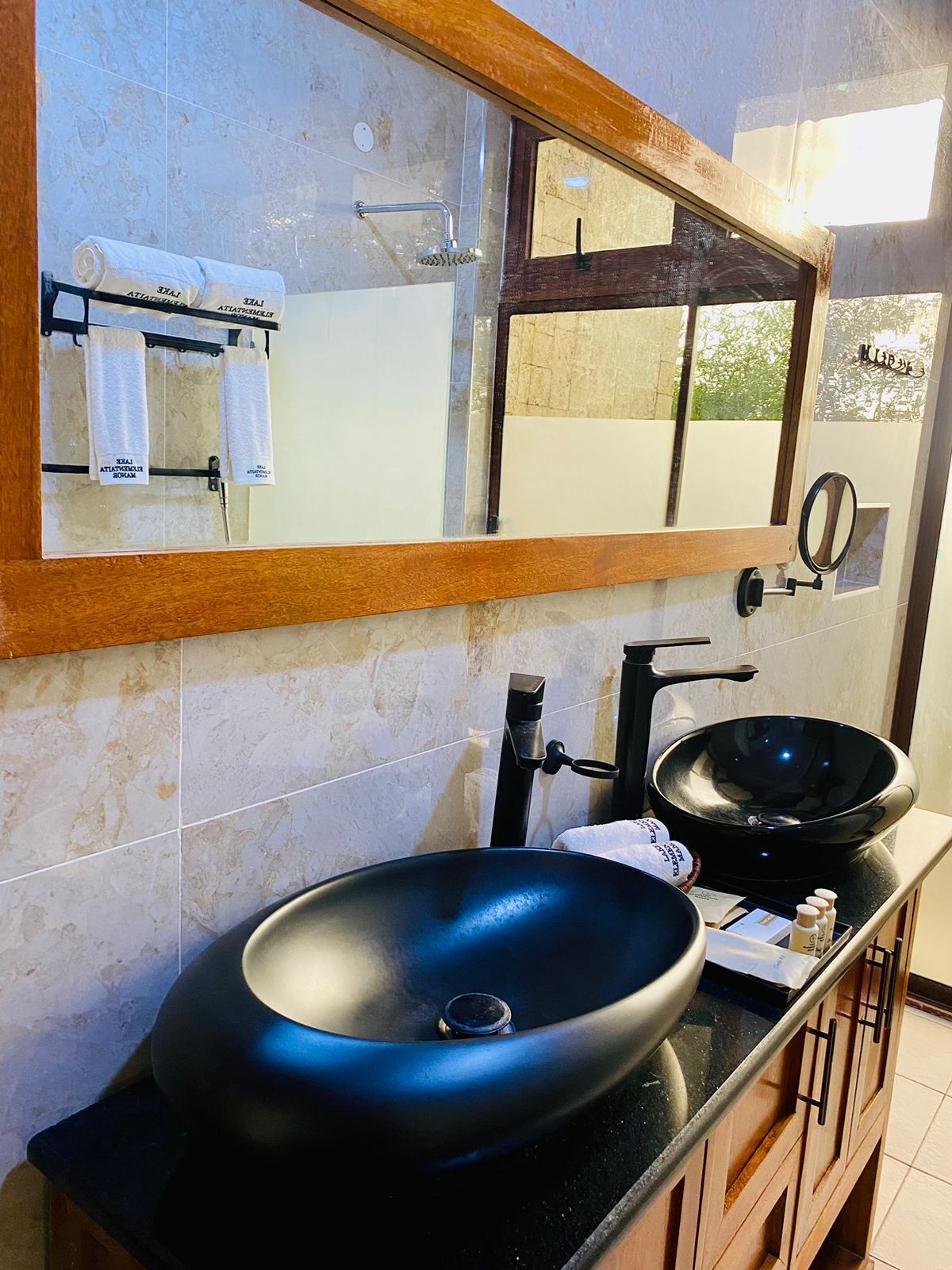 A bathroom with a black vessel sink, a mirror, and a towel rack with towels.