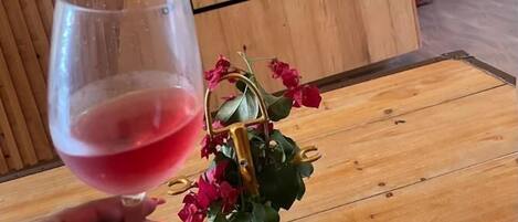 A wooden sign with "Lake Elementia Manor" written on it, a glass of red wine, and a small potted plant with red flowers.