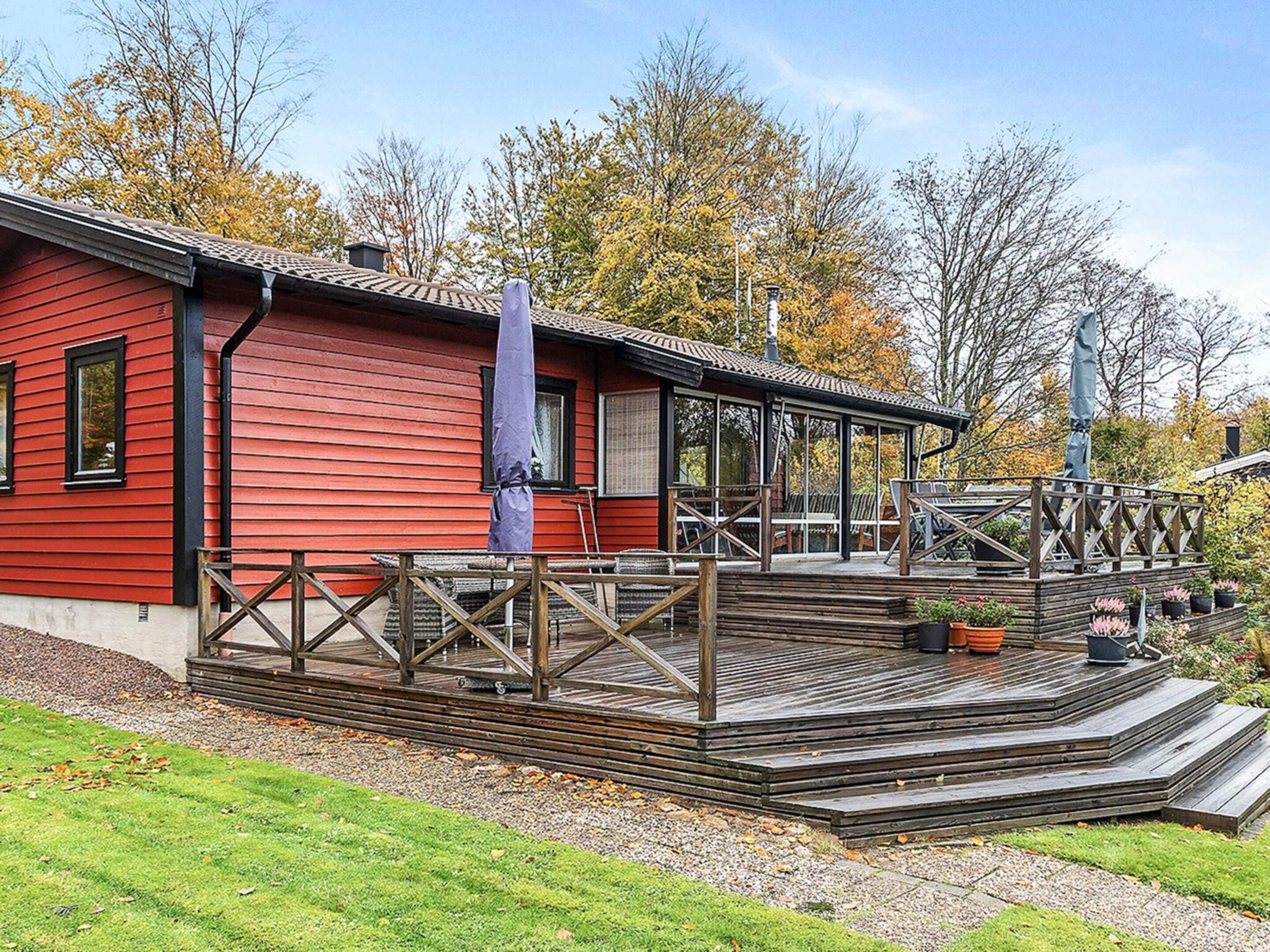 A red building with a wooden deck and a covered outdoor seating area.