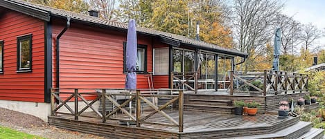 A red building with a wooden deck and a covered outdoor seating area.