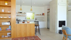 Une cuisine moderne avec des meubles en bois, un îlot central, des tabourets de bar et des luminaires suspendus.