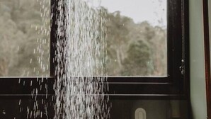 A room with a large window, a hanging light fixture, and a visible water spout.