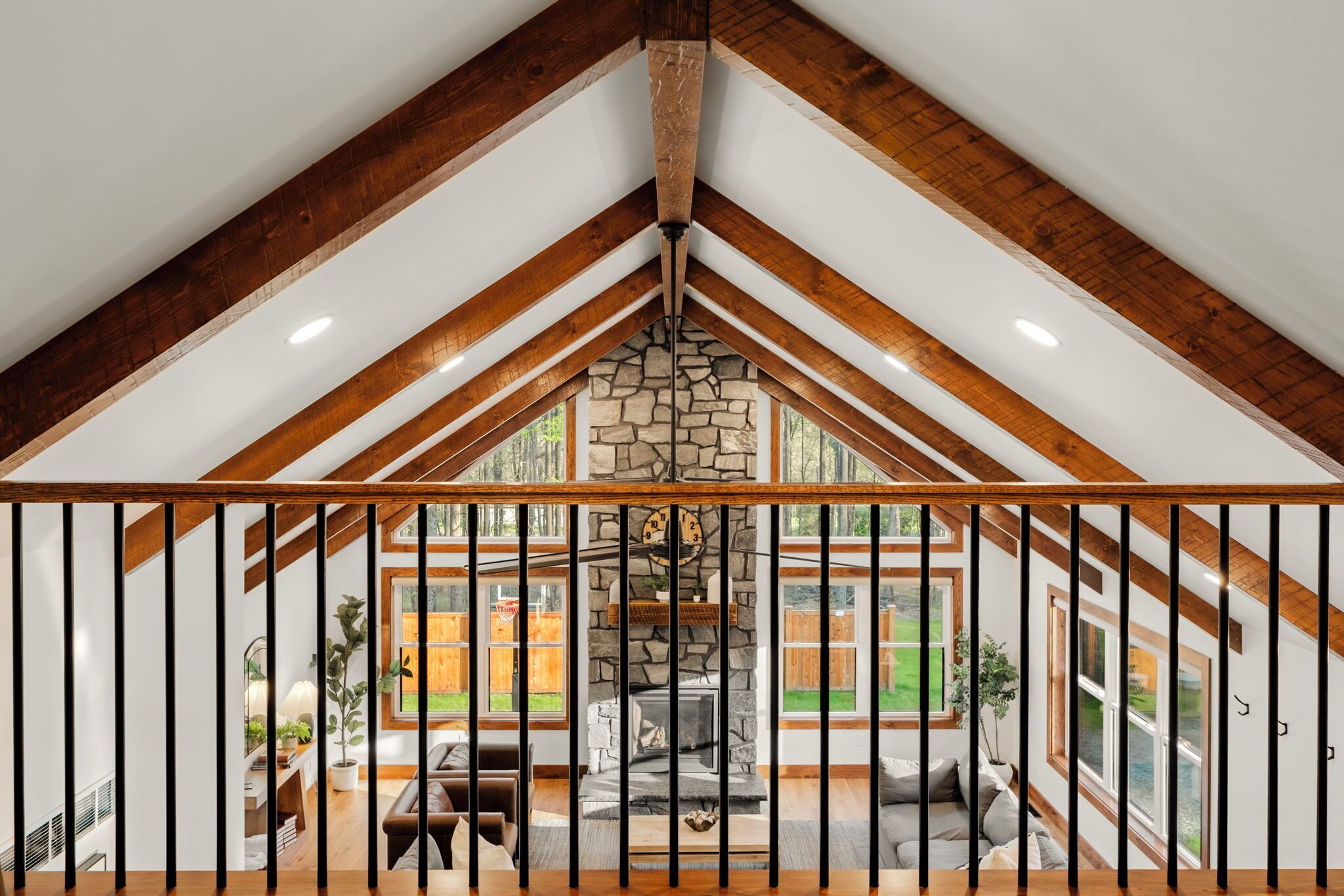 A room with a stone fireplace, wooden beams, and large windows.