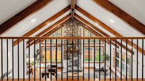 Una habitación con chimenea de piedra, vigas de madera y grandes ventanales.