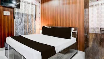 A modern bedroom with a wooden panel wall, a bed with white and black bedding, a TV mounted on the wall, and a mirror on the door.