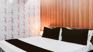 A hotel room with a bed, a wooden headboard, and a wall with a floral pattern.