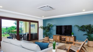 Una sala moderna con sofá, mesa de centro, televisor y plantas.