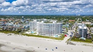 Un hotel a la costa amb un edifici circular, una platja i una marina.