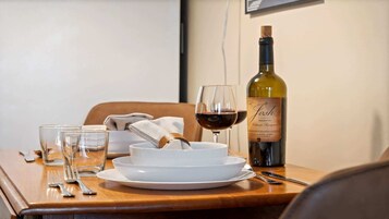 Una mesa de comedor con una botella de vino, una copa de vino tinto y un plato de comida.