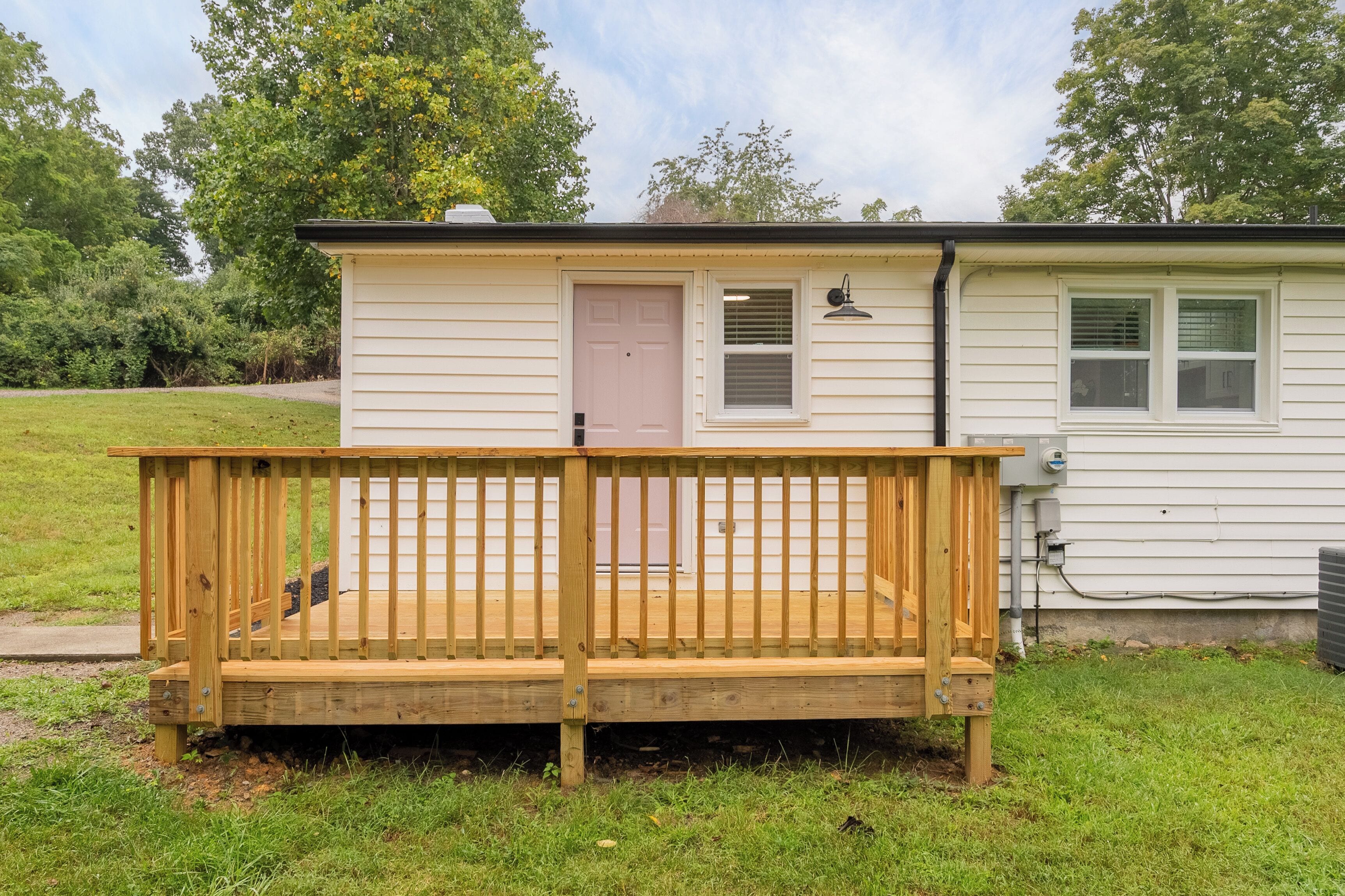 A small, single-story house with a wooden deck and a door.