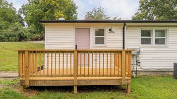 A small, single-story house with a wooden deck and a door.