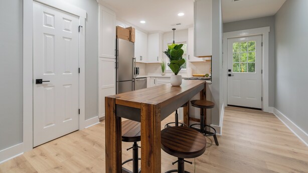 A modern kitchen with white cabinetry, a wooden bar table, and bar stools. - Modern Blacksburg retreat near VT, Radford & scenic Claytor Lake Perfect for work, play & relaxation (Blacksburg)