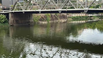 Eine Brücke über einem ruhigen Fluss, links davon ein kleines Gebäude.