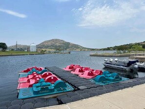 A dock with paddle boats and a boat moored at a pier.