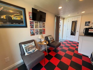 A room with two grey sofas, a small table, a wall-mounted TV, and a red and black checkered floor.