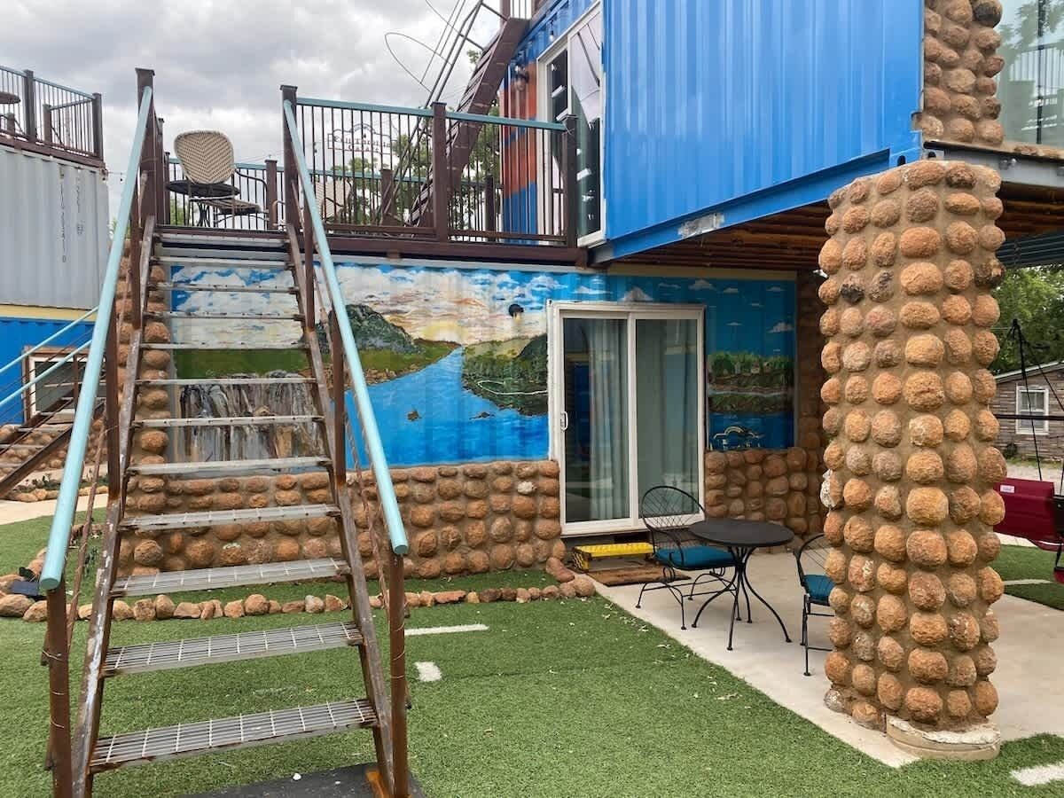 Un edificio con un pilar de piedra, una escalera y un mural con un paisaje.