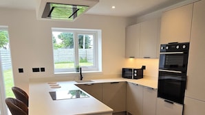 A modern kitchen with a central island, built-in appliances, and a large window providing natural light.
