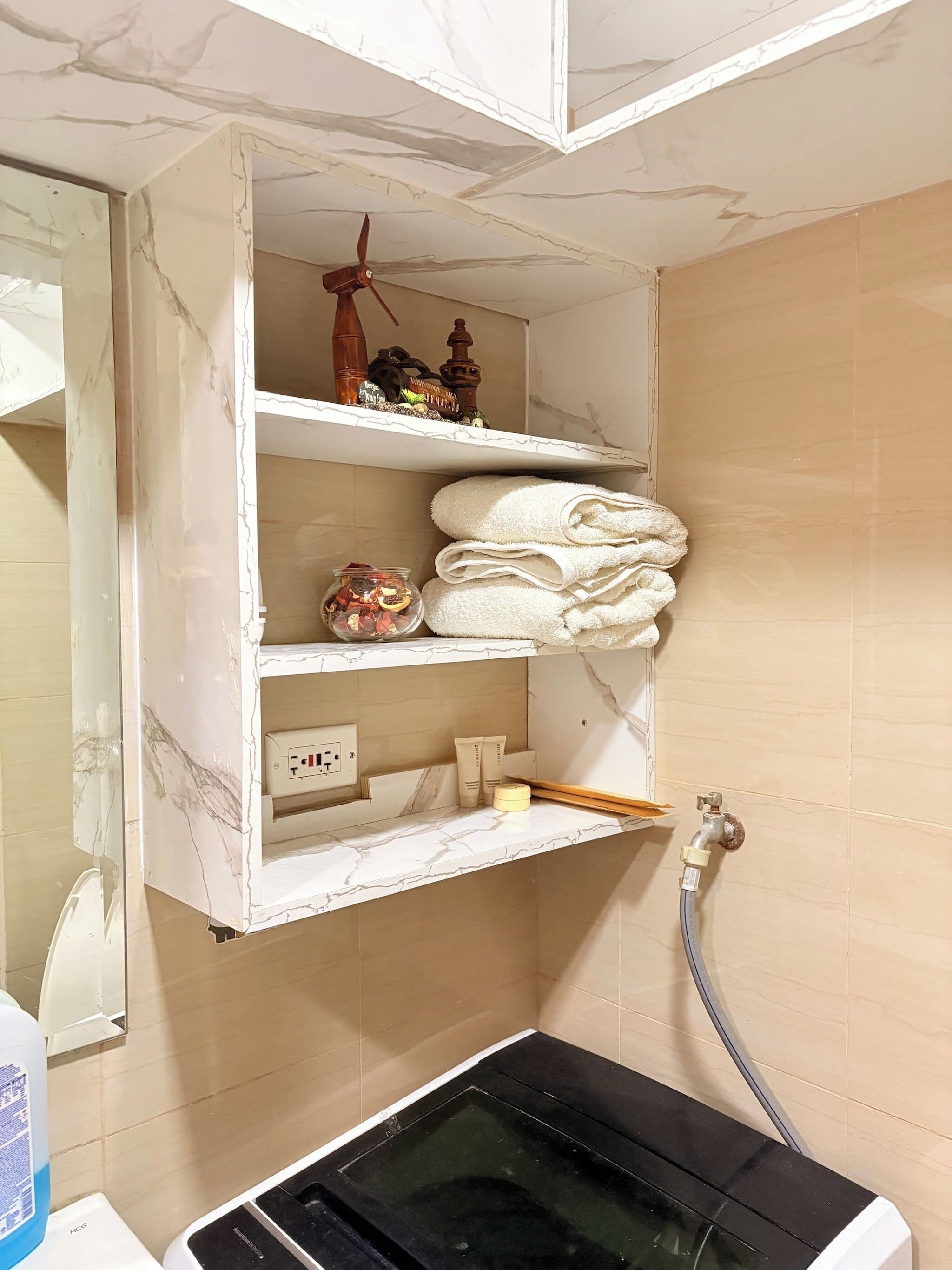 A bathroom with a marble vanity, a towel rack, a small shelf with toiletries, and a black heater.
