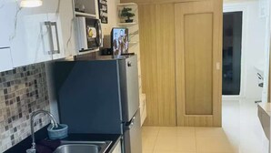 A modern kitchen with a stainless steel sink, a microwave, and a wooden door. - Metro’s Hideaway Shore Tower B (Pasay City)