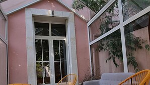 A sunlit patio with a pink wall, a glass door, and two wicker chairs. - Villa Muscat, authentic charm in the heart of town / beaches 3 kilometers (Frontignan)