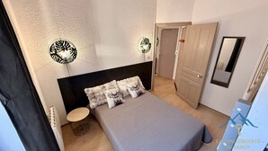 A bedroom with a bed, bedside lamps, a round table, and a wardrobe. - Villa Bleue 3 Le Mont Dore 5pers (Mont-Dore)
