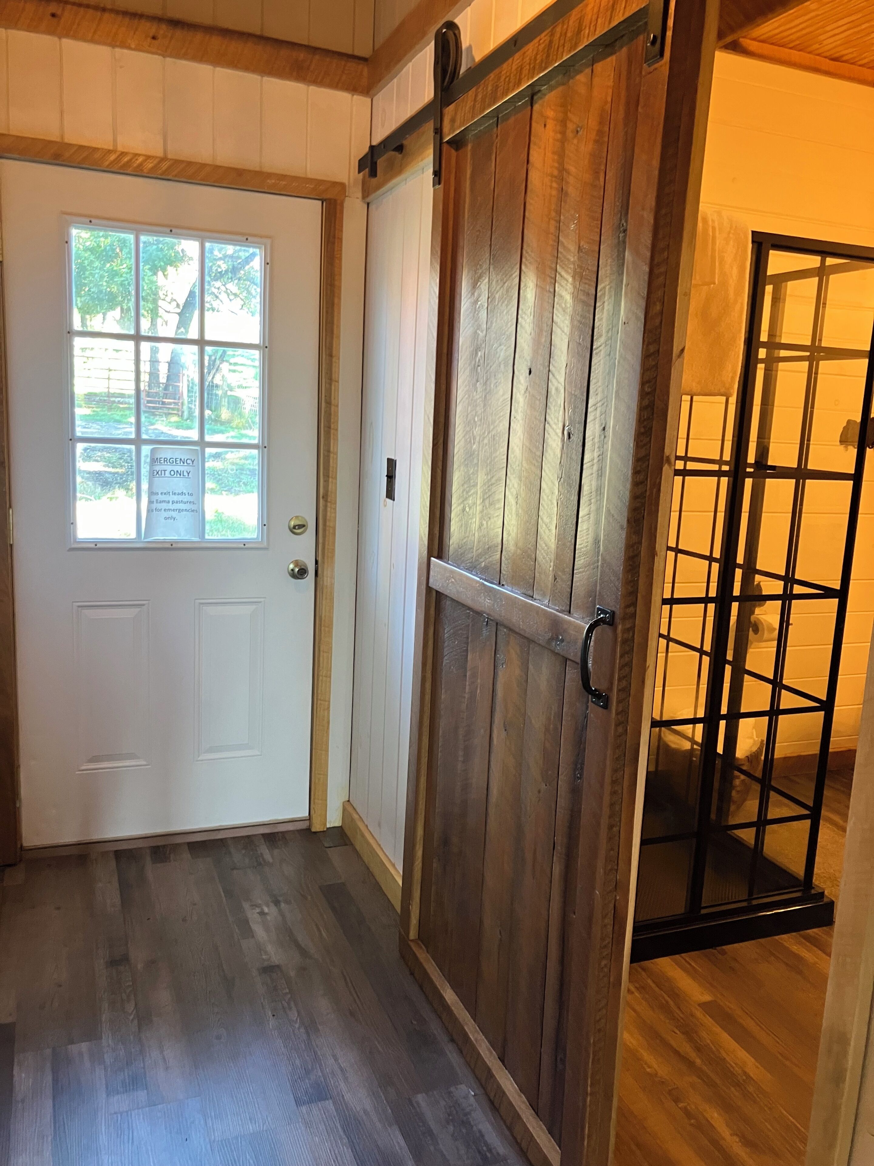 Una puerta de madera con una ventana, un portón corredero y una verja de metal.