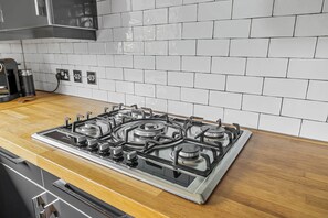 A kitchen with a stainless steel stove, wooden countertop, and white tiled backsplash.