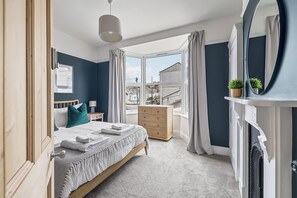 Un dormitorio con cama, cómoda y un ventanal grande.