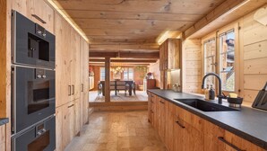 A modern kitchen with wooden cabinetry, stainless steel appliances, and a central island with a sink.