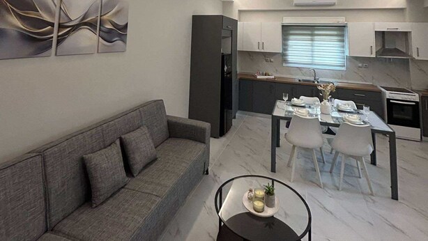 Ein modernes Wohnzimmer mit einem grauen Sofa, einem runden Couchtisch und abstrakter Wandkunst.