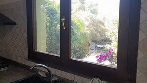 A kitchen with a window, a sink, and a stove. - House in the green between sea and countryside (San Vero Milis)