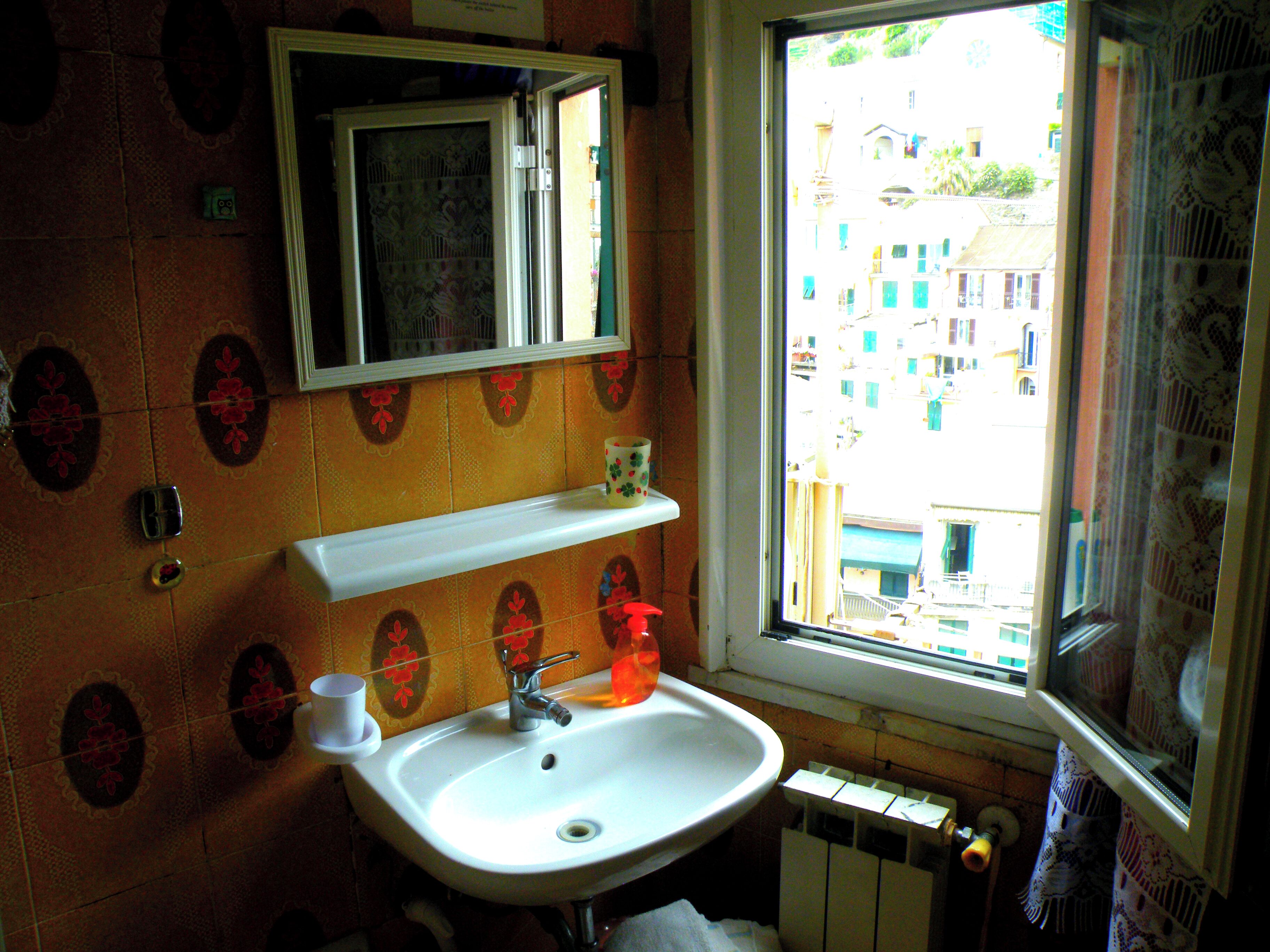 A bathroom with a sink, mirror, and window.