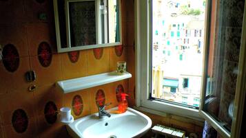 A bathroom with a sink, mirror, and window.