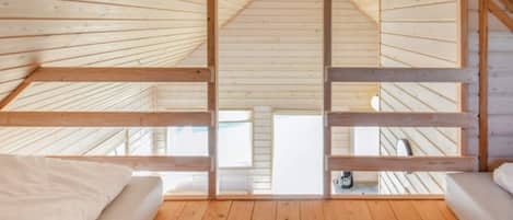 A high-ceilinged room with wooden beams, two beds, and skylights.