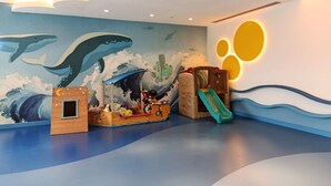 A children's play area with a mural of whales and a slide.