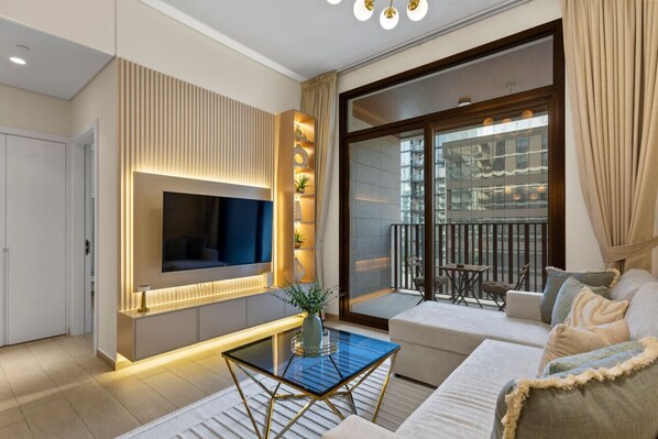 A modern living room with a TV, a glass coffee table, and a sofa.