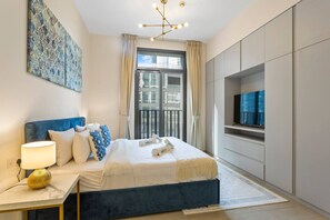 A modern bedroom with a large bed, a bedside table with a lamp, a TV, and a view of the city through the window.