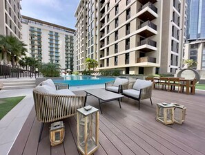 A poolside area with wicker furniture, a small table, and lanterns.
