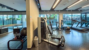 A modern gym with cardio machines, weight training equipment, and a bench.