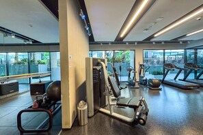 A modern gym with cardio machines, weight training equipment, and a bench. - Art-Inspired 1 Bedroom in Wilton Terraces (Dubai)