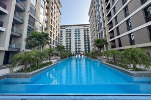 A modern hotel with a central swimming pool surrounded by palm trees and high-rise buildings. - Art-Inspired 1 Bedroom in Wilton Terraces (Dubai)