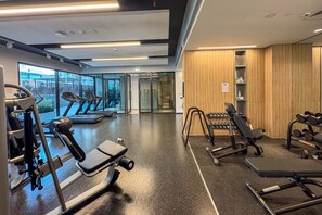 A modern gym with treadmills, weight machines, and dumbbells.