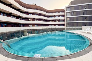 A swimming pool surrounded by a multi-story building with balconies.