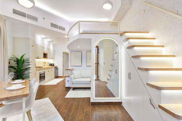 A modern interior with a dining area, kitchen, and staircase.